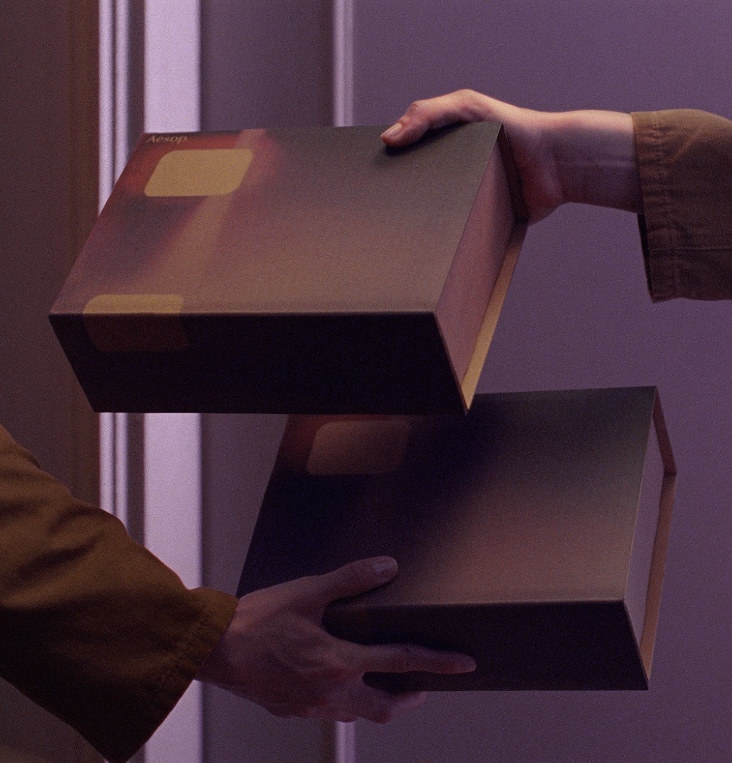 Hands holding a cardboard gift box in purple background