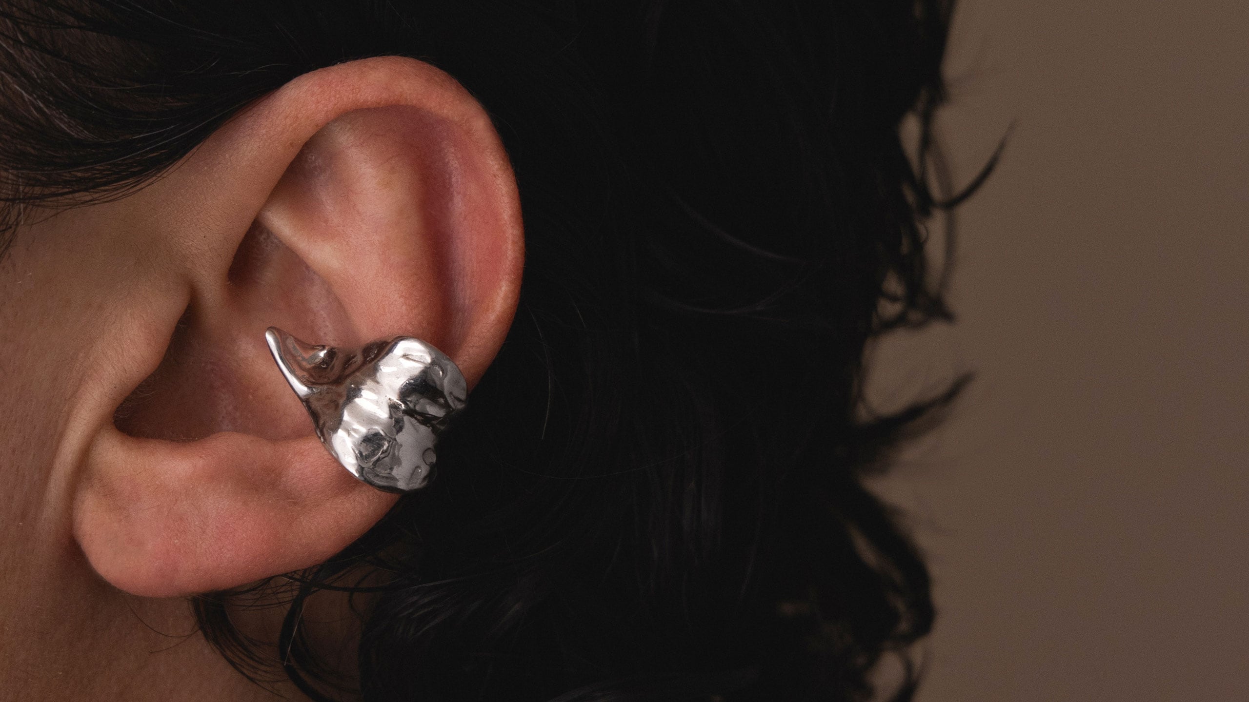 An individual wearing a silver ear cuff on a ear